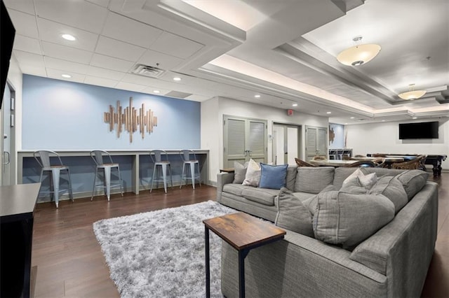 living room featuring dark wood-type flooring and a tray ceiling