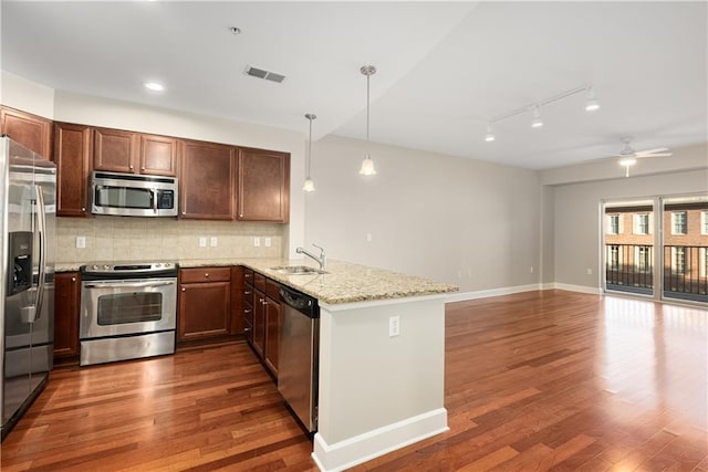 kitchen featuring decorative light fixtures, kitchen peninsula, sink, light stone countertops, and appliances with stainless steel finishes