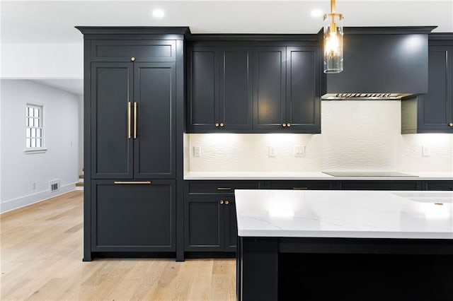 kitchen with light hardwood / wood-style floors, black electric stovetop, wall chimney range hood, and hanging light fixtures