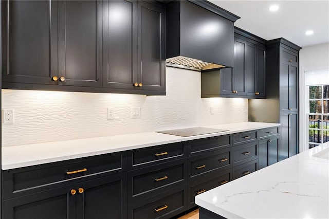 kitchen featuring tasteful backsplash, black electric stovetop, light stone counters, and wall chimney exhaust hood