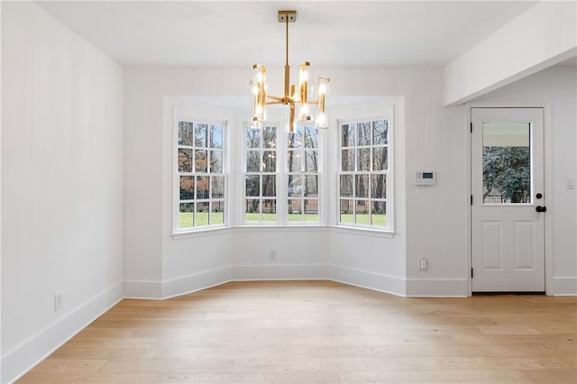 unfurnished dining area with a notable chandelier, a wealth of natural light, and light hardwood / wood-style flooring