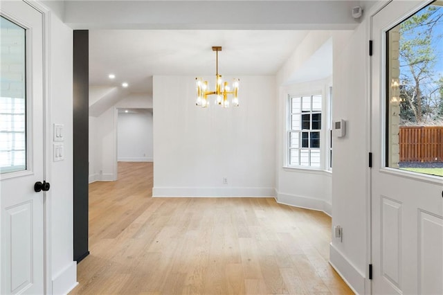 unfurnished dining area featuring an inviting chandelier and light hardwood / wood-style flooring