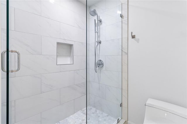 bathroom with a shower with shower door and toilet