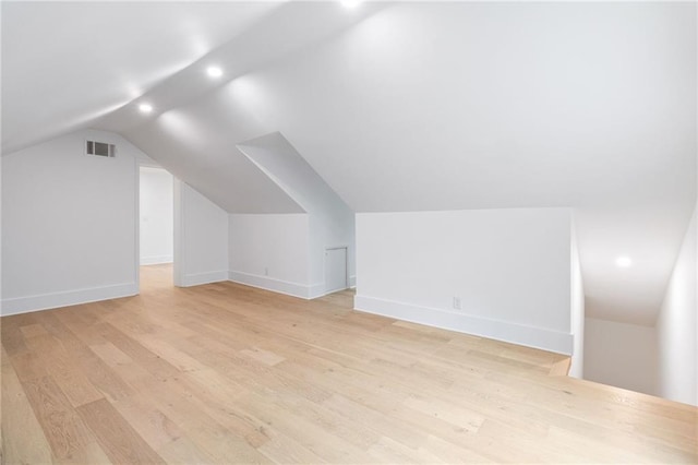 additional living space featuring vaulted ceiling and light hardwood / wood-style flooring