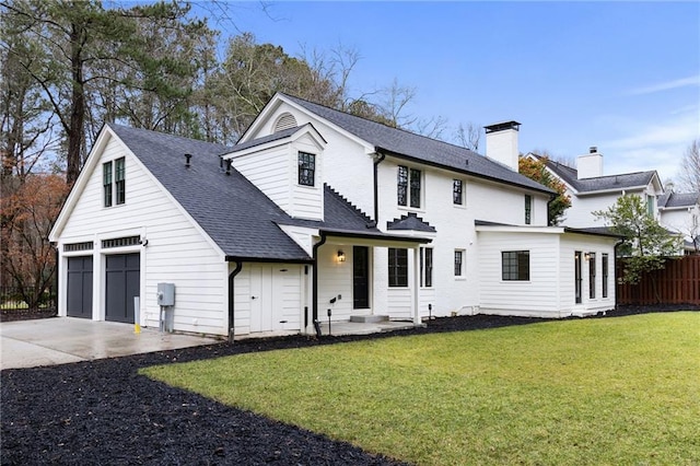 rear view of property featuring a garage, a lawn, and a patio area