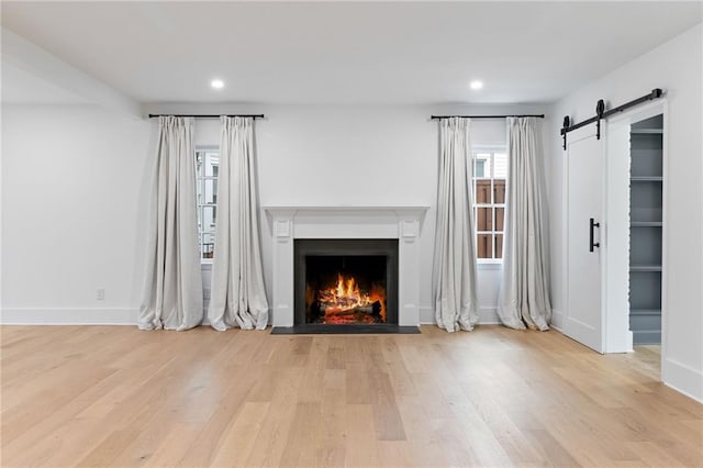 unfurnished living room featuring a barn door and light wood-type flooring