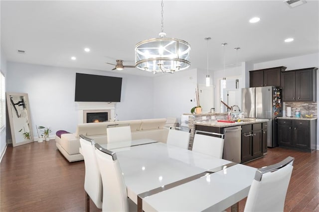 2040 Harvest Ridge Cir, Buford, GA 30519 - dining area with a chandelier, dark wood-style floors, recessed lighting, a warm lit fireplace, and baseboards