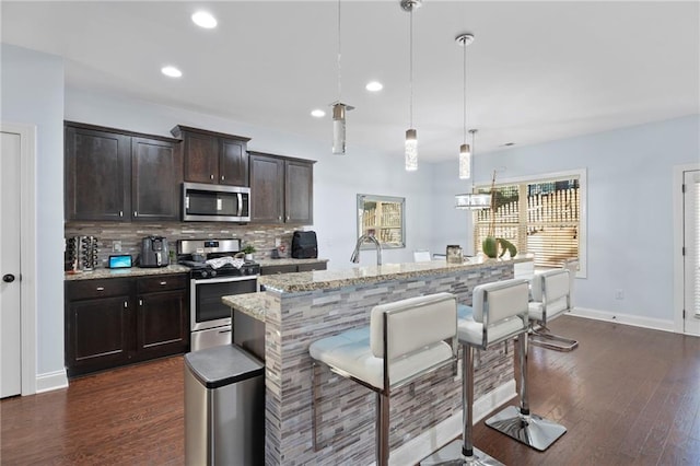 2040 Harvest Ridge Cir, Buford, GA 30519 - kitchen featuring appliances with stainless steel finishes, a breakfast bar, tasteful backsplash, recessed lighting, and light stone counters