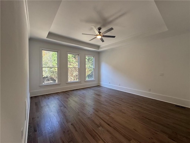 spare room featuring a tray ceiling, ceiling fan, and dark hardwood / wood-style floors