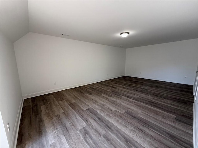 spare room with hardwood / wood-style floors and vaulted ceiling