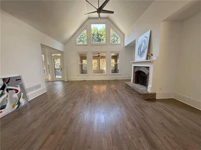 unfurnished living room with a stone fireplace, ceiling fan, dark hardwood / wood-style flooring, and high vaulted ceiling