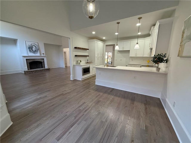 kitchen featuring dark hardwood / wood-style flooring, sink, pendant lighting, white cabinets, and oven