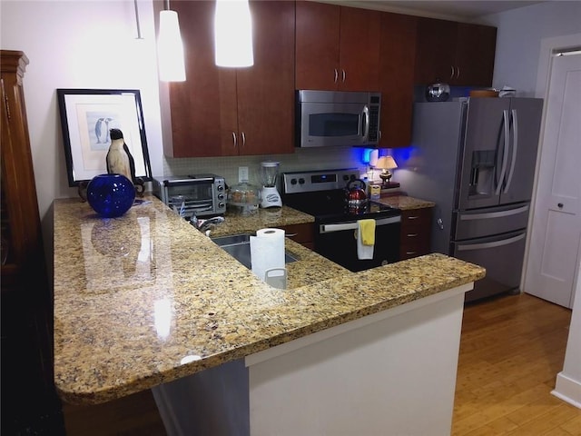 3655 Peachtree Rd Unit 203, Atlanta, GA 30319 - kitchen featuring appliances with stainless steel finishes, light wood-style floors, light stone countertops, and a peninsula