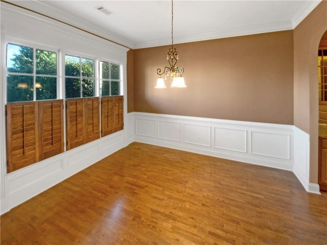 empty room with ornamental molding, a chandelier, and wood-type flooring