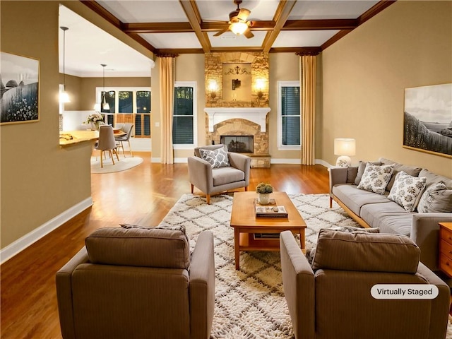 living room featuring hardwood / wood-style flooring, ceiling fan, a stone fireplace, and coffered ceiling