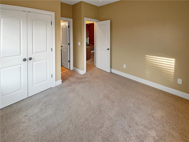 unfurnished bedroom with light colored carpet and a closet