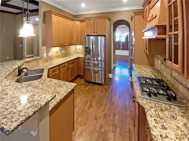 kitchen featuring hardwood / wood-style floors, sink, hanging light fixtures, decorative backsplash, and appliances with stainless steel finishes