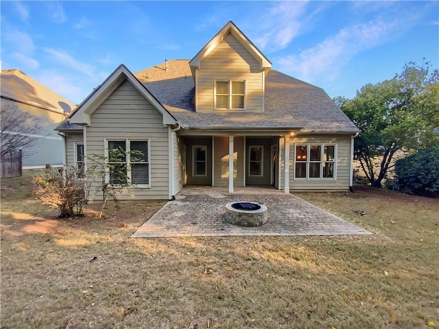 rear view of house featuring a patio area, a yard, and a fire pit