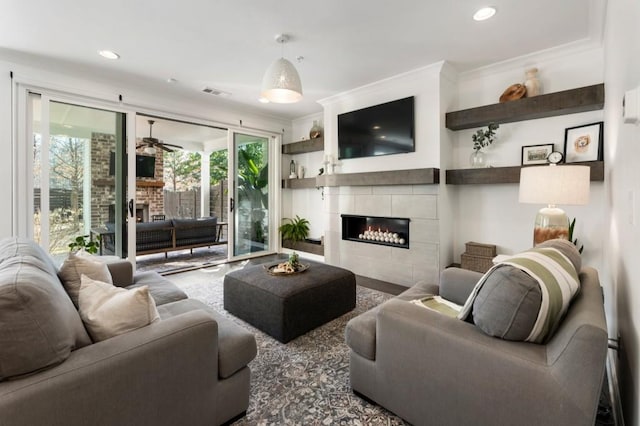 living area with crown molding, recessed lighting, visible vents, and a fireplace