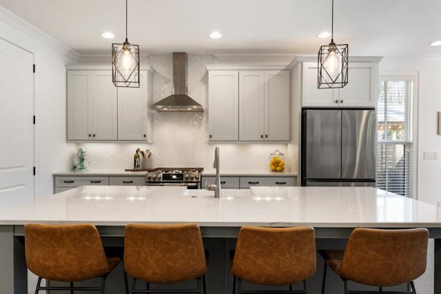 kitchen with stainless steel appliances, light countertops, backsplash, a sink, and wall chimney exhaust hood