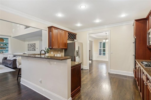 kitchen with a kitchen bar, appliances with stainless steel finishes, open floor plan, and dark wood-style flooring