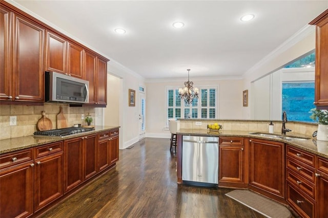 kitchen featuring appliances with stainless steel finishes, dark hardwood / wood-style flooring, sink, hanging light fixtures, and light stone counters