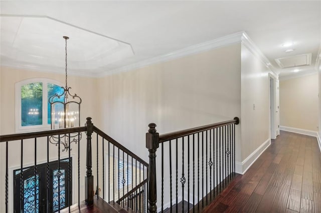 hallway featuring wood finished floors, an upstairs landing, baseboards, an inviting chandelier, and crown molding