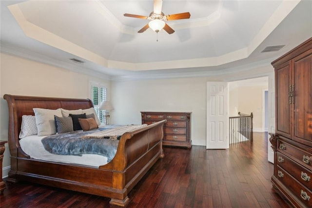 bedroom with a tray ceiling, dark wood-type flooring, and visible vents