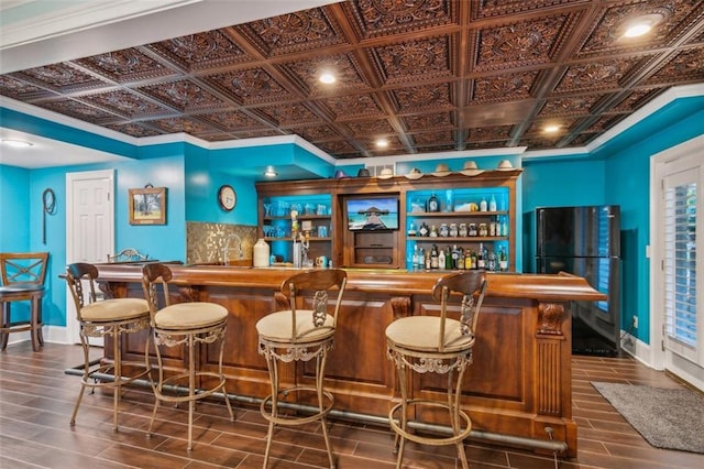 bar with an ornate ceiling, indoor wet bar, tasteful backsplash, freestanding refrigerator, and baseboards