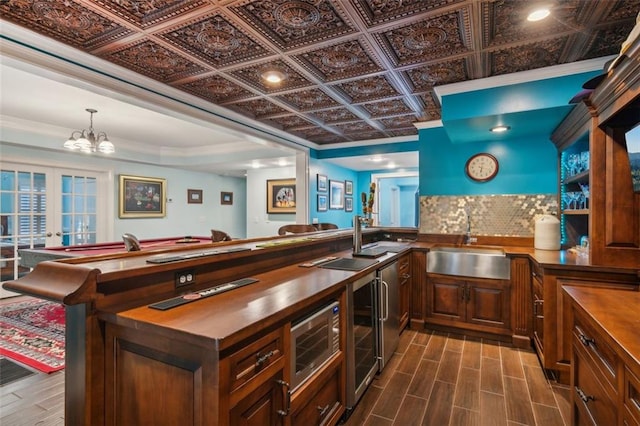 bar featuring wooden counters, decorative backsplash, sink, french doors, and beverage cooler