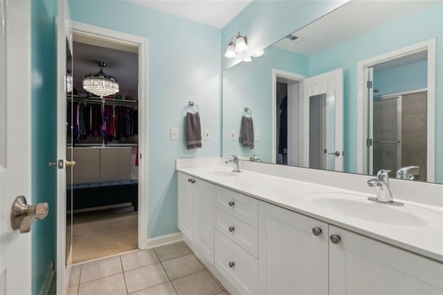 bathroom featuring double vanity, tile patterned flooring, a walk in closet, and a sink