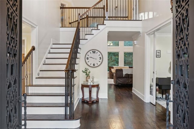 entrance foyer featuring stairs, a high ceiling, wood finished floors, and baseboards