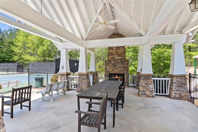 view of patio featuring ceiling fan, fence, an outdoor stone fireplace, and a gazebo