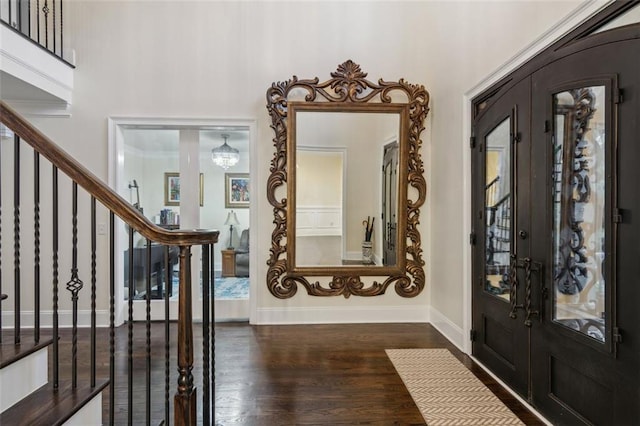 foyer featuring dark hardwood / wood-style flooring, an inviting chandelier, and french doors