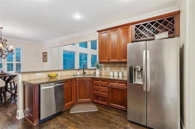 kitchen featuring crown molding, decorative backsplash, appliances with stainless steel finishes, a sink, and dark stone countertops