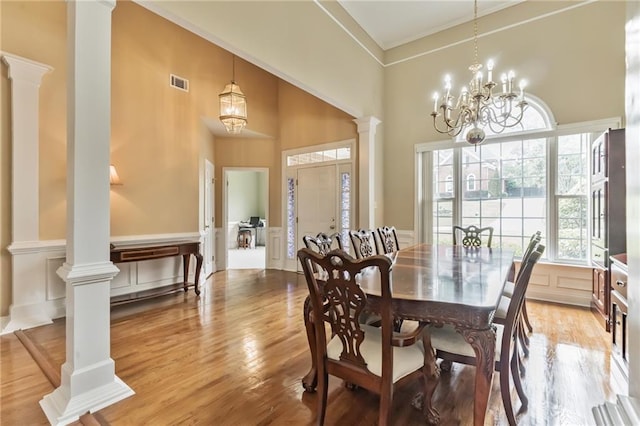 656 Deerwood Way, Evans, GA 30809 - dining space featuring decorative columns, a towering ceiling, a chandelier, ornamental molding, and light wood-type flooring