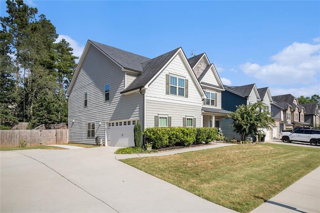 view of front of property featuring an attached garage, driveway, a front yard, and fence