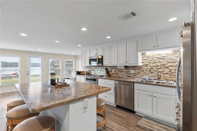 kitchen featuring a kitchen bar, a center island, stainless steel appliances, and sink