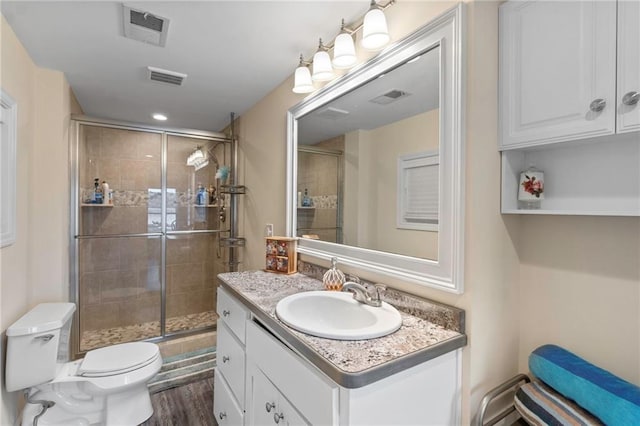 bathroom with hardwood / wood-style floors, vanity, toilet, and walk in shower