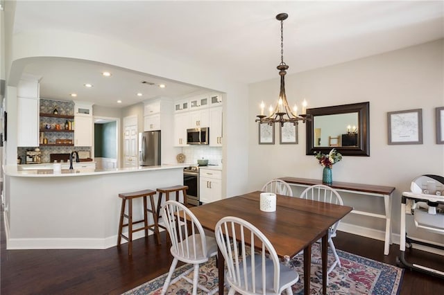 dining space with recessed lighting, arched walkways, baseboards, a chandelier, and dark wood-style flooring