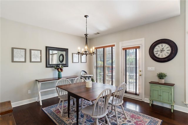 dining area with dark wood-type flooring, baseboards, and a chandelier