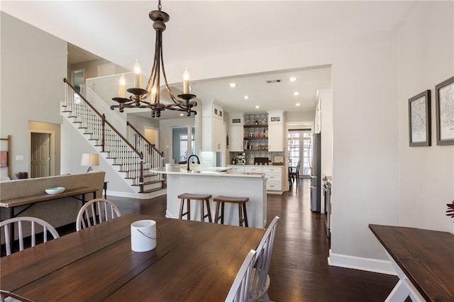 dining area featuring dark wood-type flooring, stairway, baseboards, and a chandelier