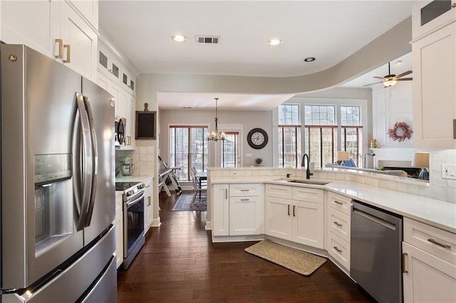 kitchen with visible vents, decorative backsplash, appliances with stainless steel finishes, a peninsula, and a sink