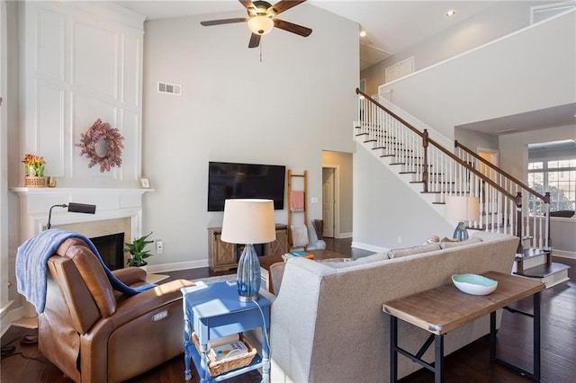 living room with visible vents, dark wood finished floors, stairway, a high ceiling, and ceiling fan