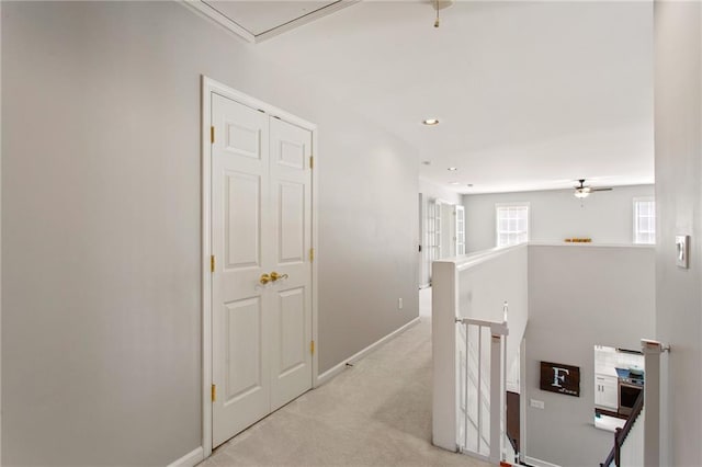 hallway with recessed lighting, an upstairs landing, baseboards, and light carpet