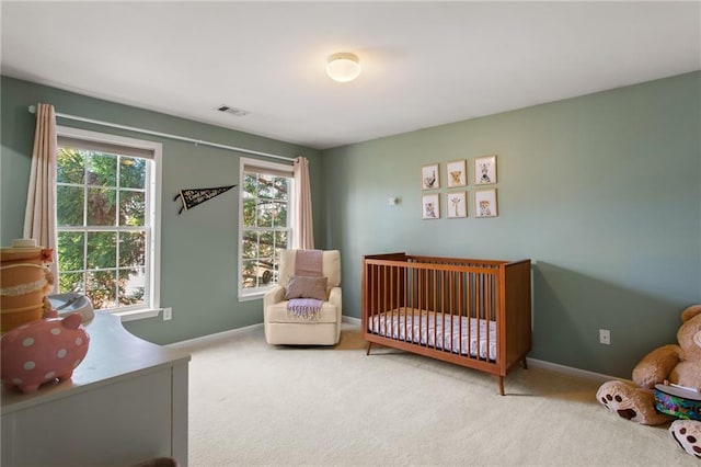 bedroom featuring a nursery area, carpet flooring, visible vents, and baseboards