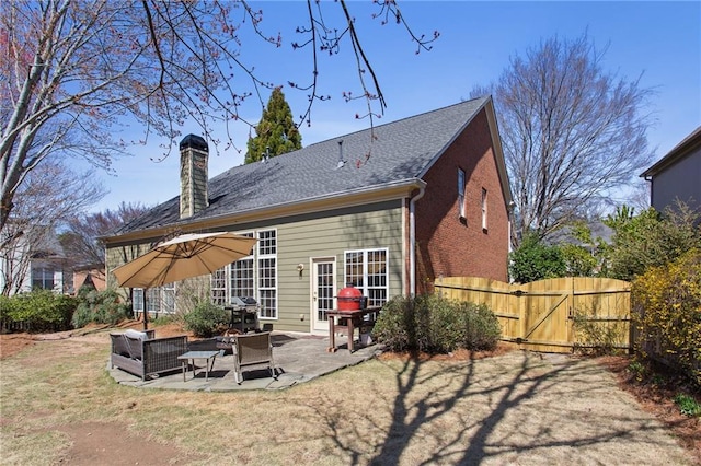 back of property with fence, a chimney, a yard, a patio area, and a gate