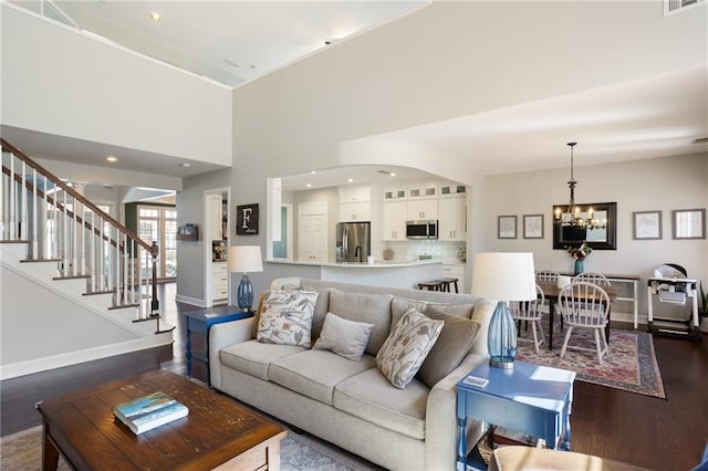 living room with baseboards, a notable chandelier, dark wood-style floors, and stairs