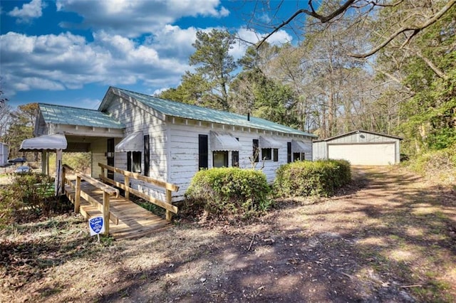 view of property exterior with an outdoor structure, a garage, driveway, and metal roof