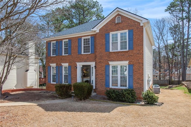 colonial-style house featuring brick siding and central AC